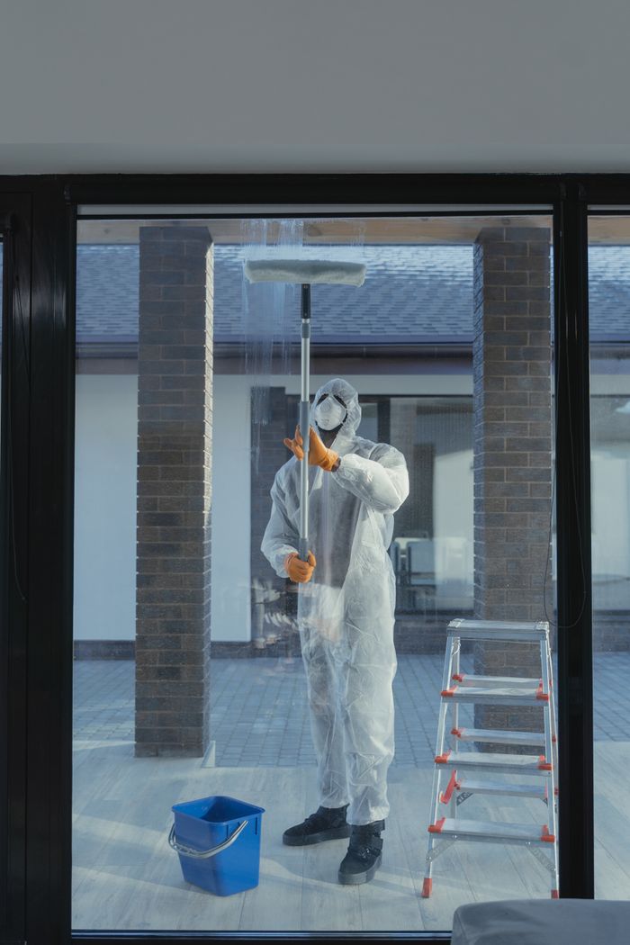 Projects A man in full protective gear cleaning a glass window during the daytime.