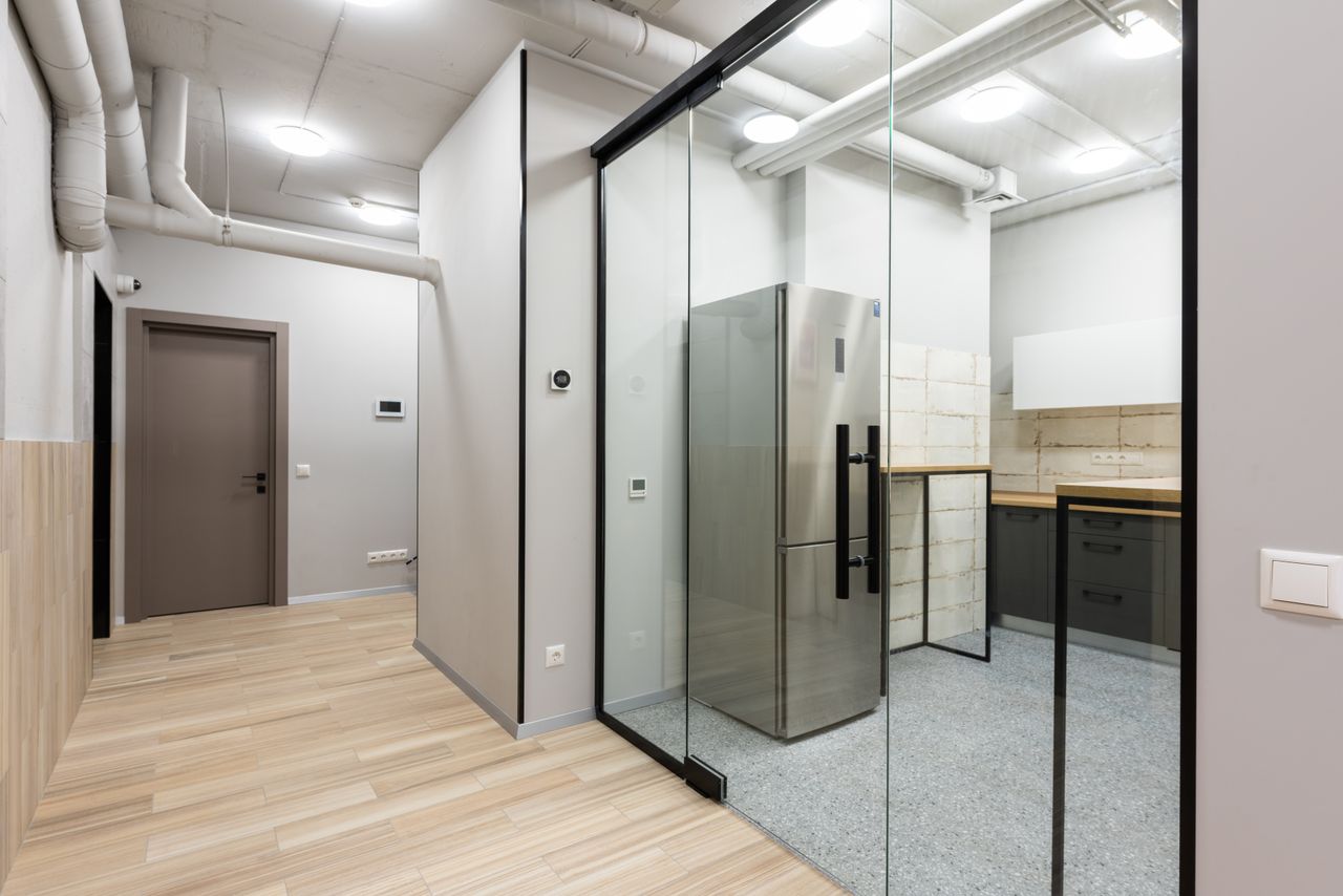 Projects Interior of spacious hallway and kitchen with counters and appliances in contemporary workplace