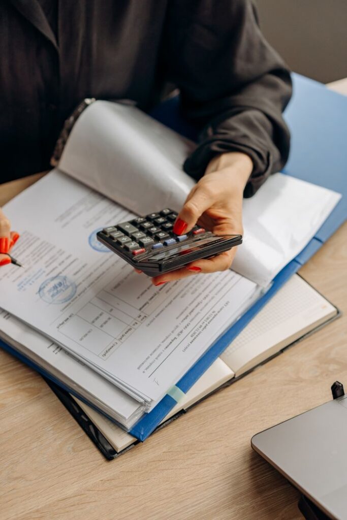 pexels photo 8297030 8297030 Person using calculator and documents for accounting tasks in an office setting.
