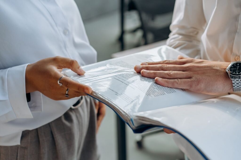 pexels photo 8297652 8297652 Two professionals examining business documents during a meeting indoors.
